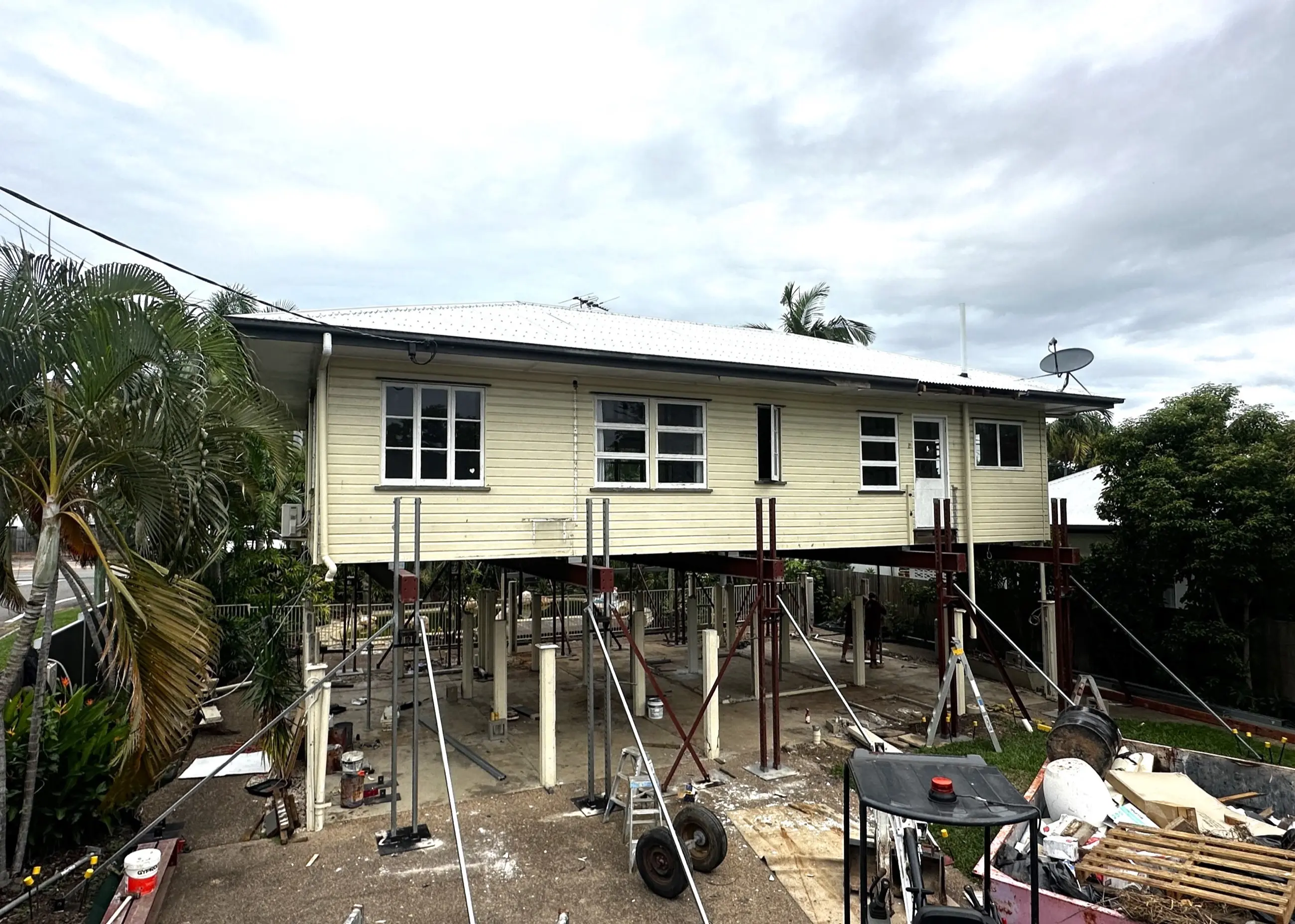 A weatherboard house held on steel props while its new lower level is being constructed