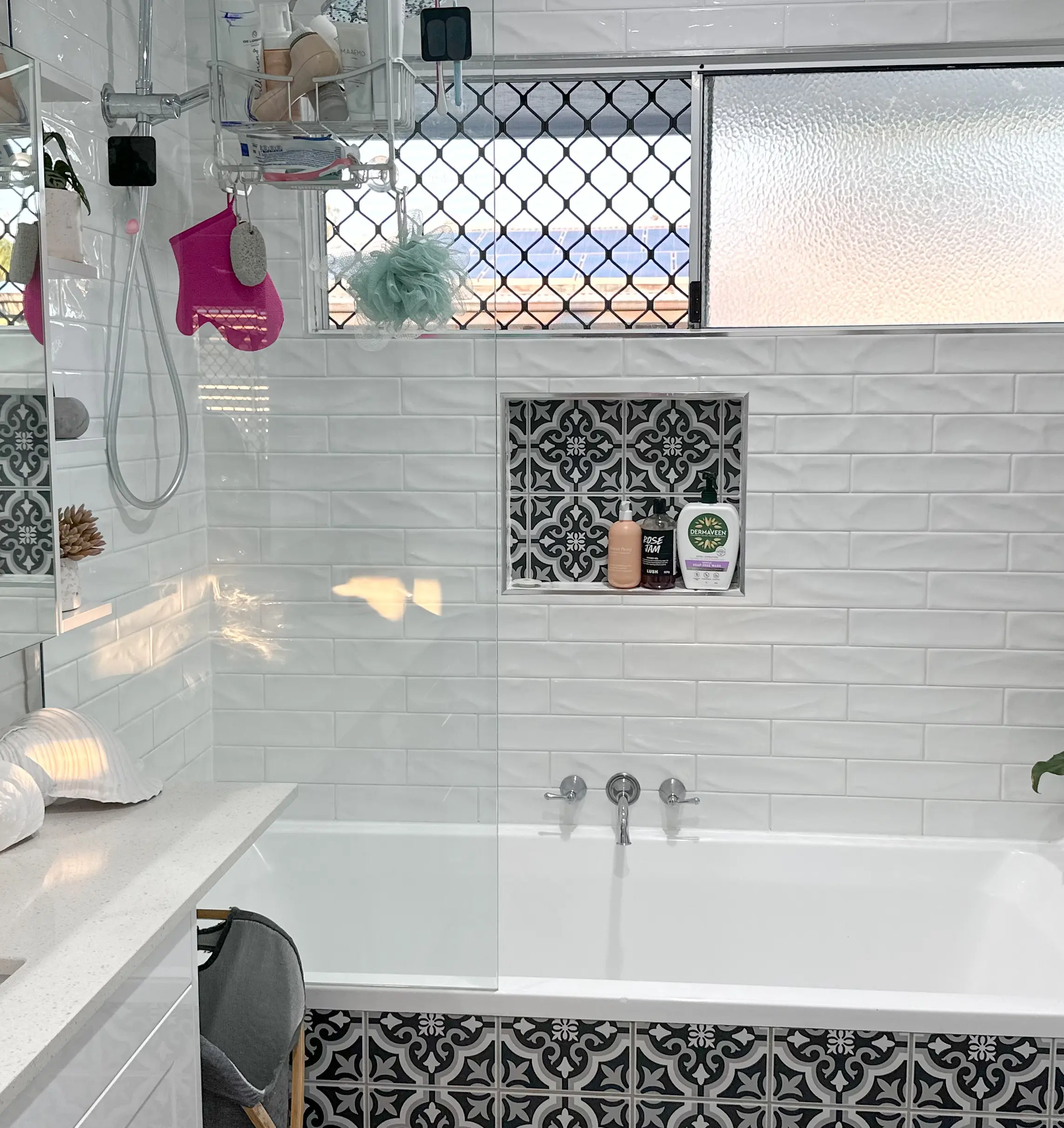 A freestanding bath beside a patterned tiled niche