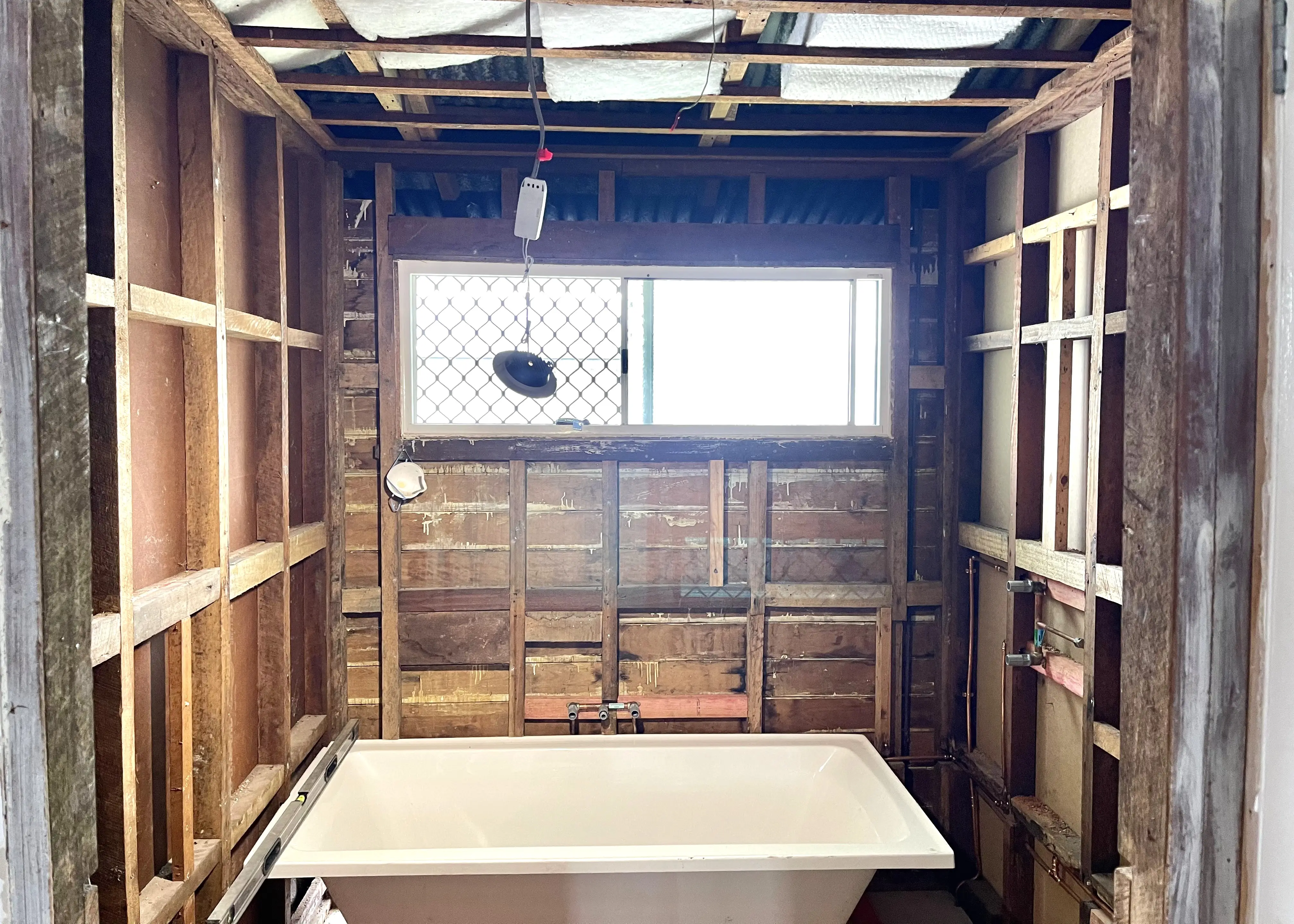 A bathroom stripped back to studs with the new bath set in place