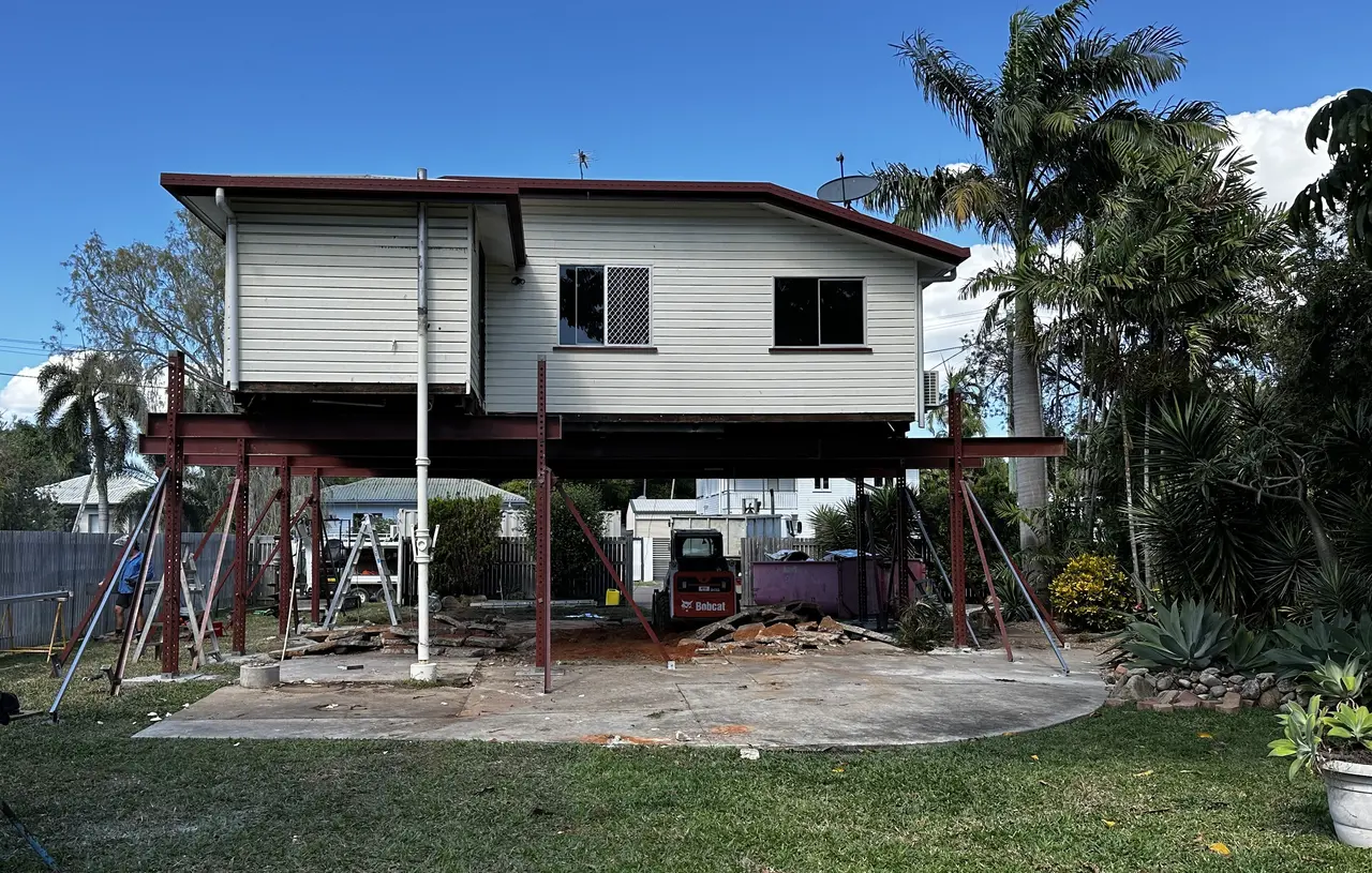 A house supported on a beam-and-prop rig part way through a lift