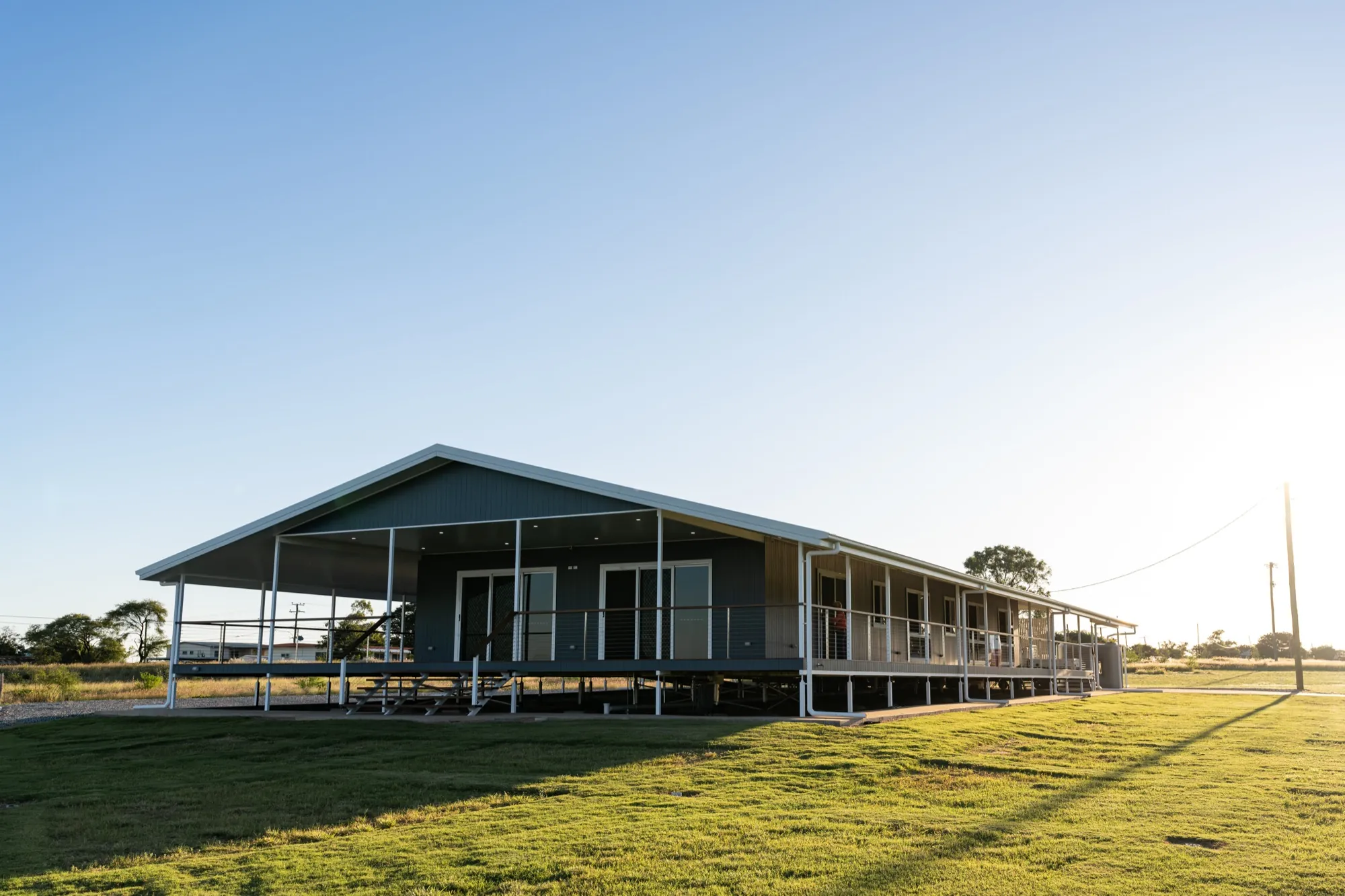 A completed JKC custom home at dusk — wide verandahs and timber entry
